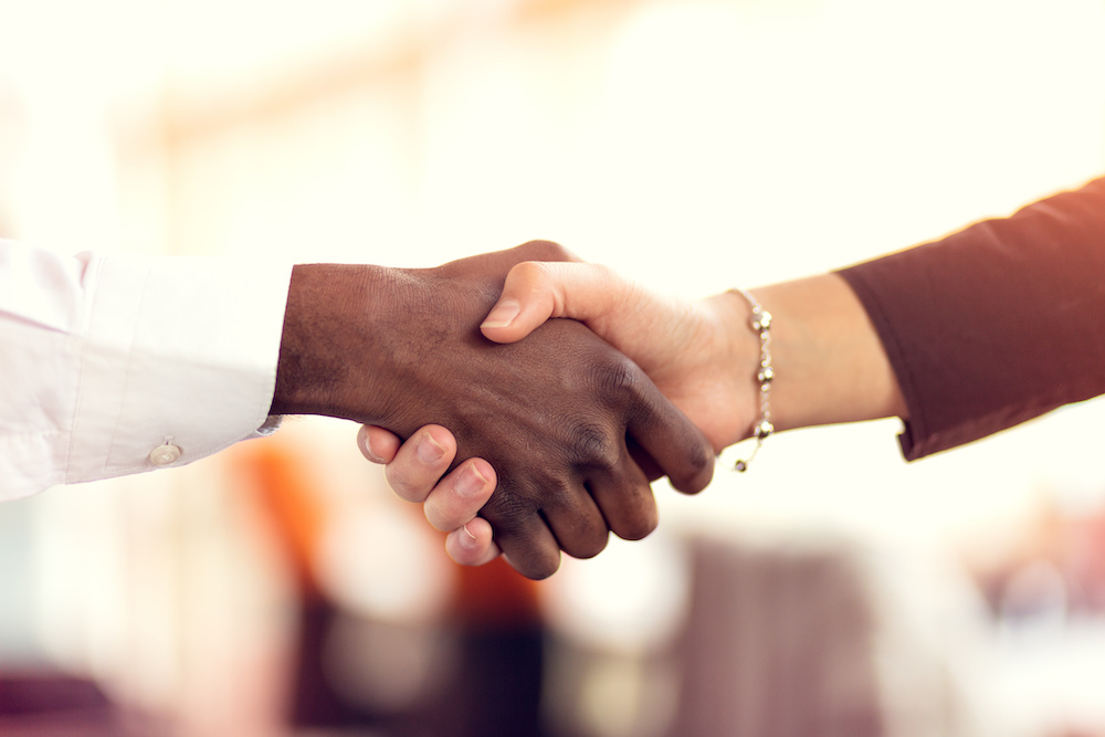 Closeup of White and Black shaking hands over a deal.